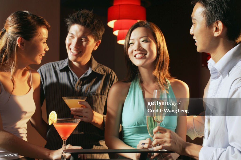Couples in night club, holding drinks