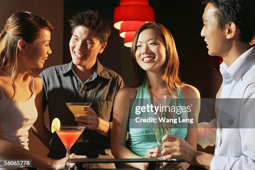 Couples in night club, holding drinks Couples in night club, holding drinks
