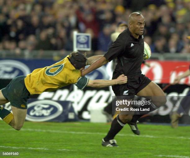 All Black Jonah Lomu fends off Wallaby Stephen Larkham on the the way to scoring the winning try in the Tri Nations match at Stadium Australia,...