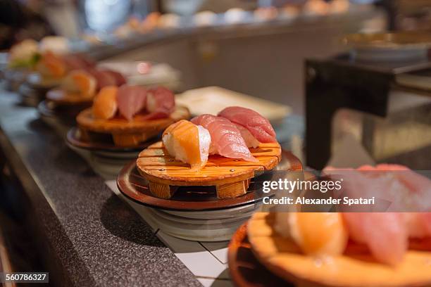 sushi on conveyor belt - bar à sushis photos et images de collection