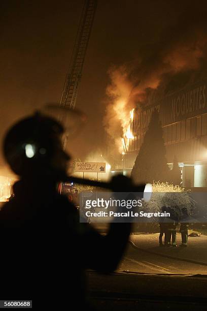 Policeman keeps watch over a warehouse set ablaze in the early hours on November 4, 2005 in Aulnay-sous-Bois, outside Paris, France. French...