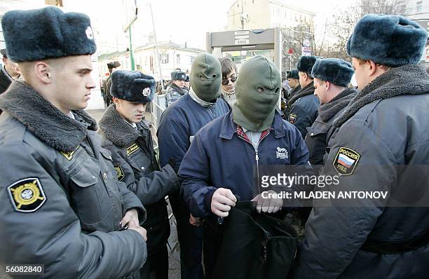 Moscow, RUSSIAN FEDERATION: Russian policemen check masked protestors during a march called by several ultranationalist organizations, marking the...