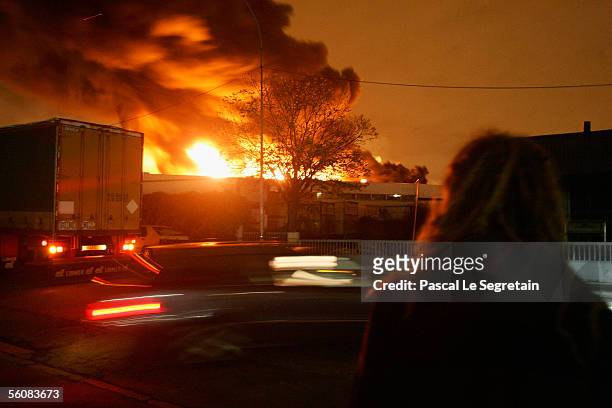 An passer by looks on at a warehouse set ablaze in the early hours on November 4, 2005 in Aulnay-sous-Bois, Paris, France. Riots continue on the...