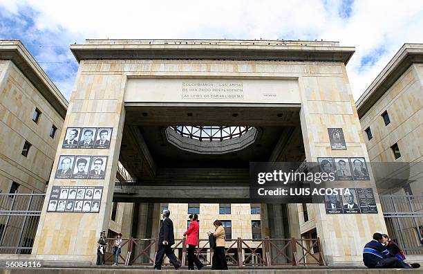 Personas pasan frente al Palacio de Justicia en Bogota el 4 de octubre de 2005, en cuya fachada han colocado fotos en homenaje de los magistrados...