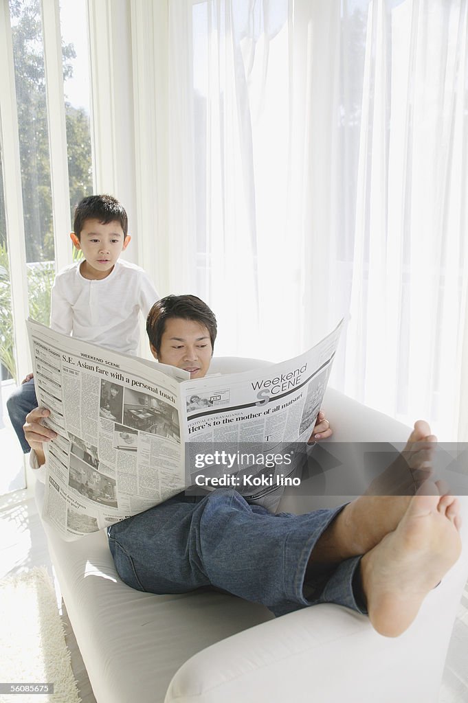 Father reading newspaper in sofa