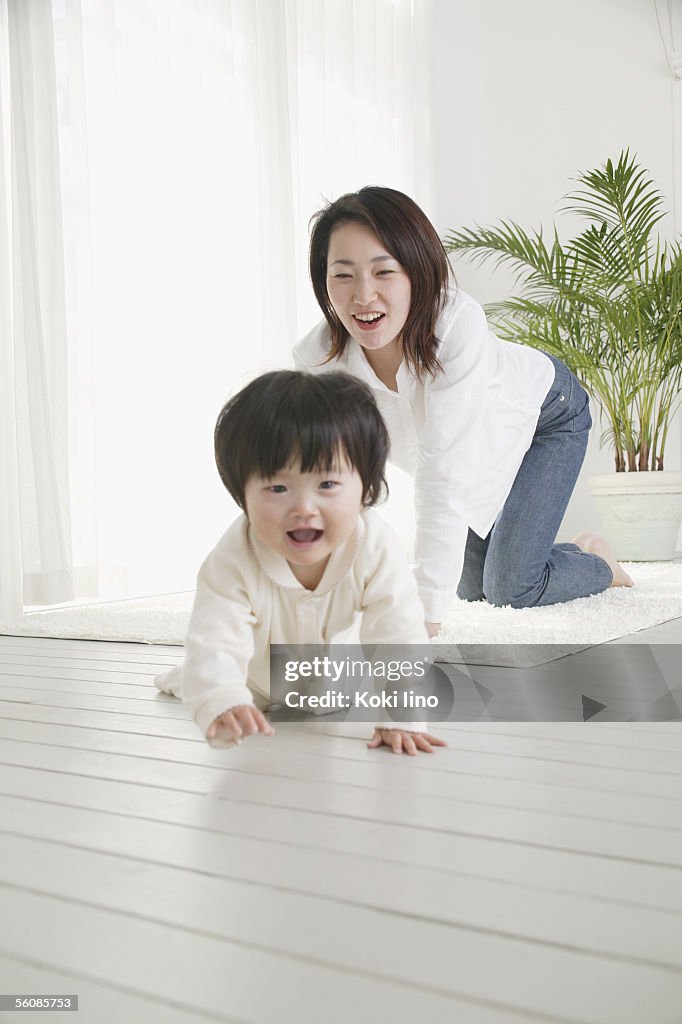 Baby girl crawling and mother following