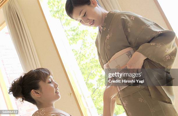 two women tying obi sash - obi sash fotografías e imágenes de stock