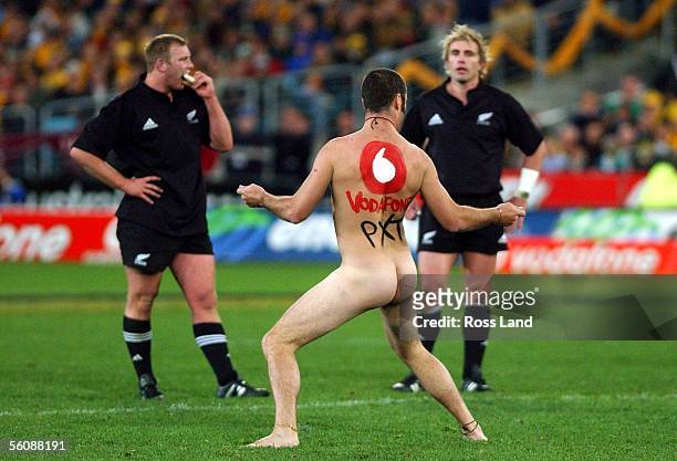 Tom Willis and Justin Marshall look less than impressed as one of two streakers who invaded the field, holds up play during the Wallabies last minute...