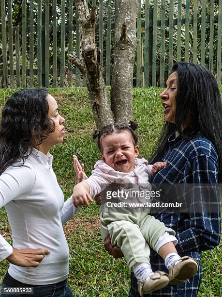 women talking with a child crying. - mulheres photos et images de collection