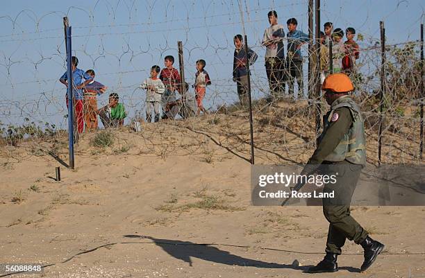 Fijian soldier of the Multinational Peackeeping Force and Observers, patrols the perimiter fence at camp One Bravo, watched by beduin children, as...