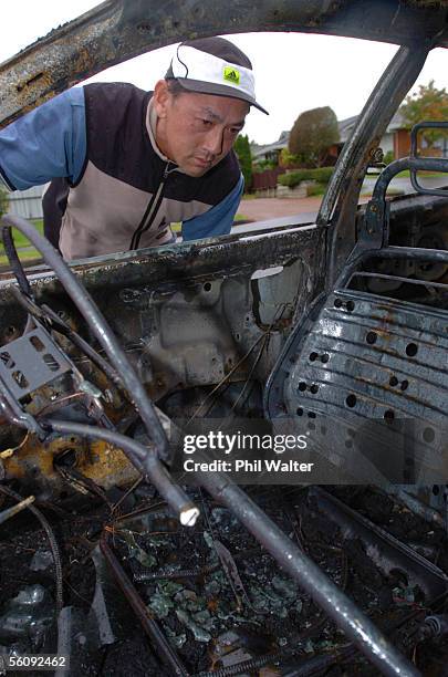 Alex Wong looks over his burned out Honda Civic in Northpark Ave, Botany Downs, after it was set alight in an arson attack that involved a further 10...