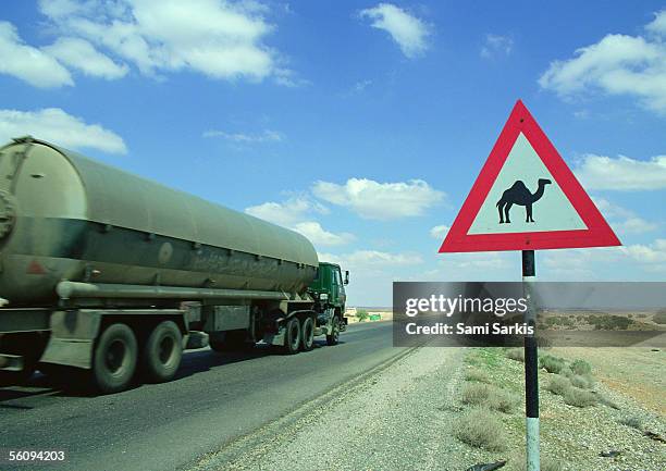 jordan, tanker on road next to camel crossing sign - camel crossing sign stock pictures, royalty-free photos & images