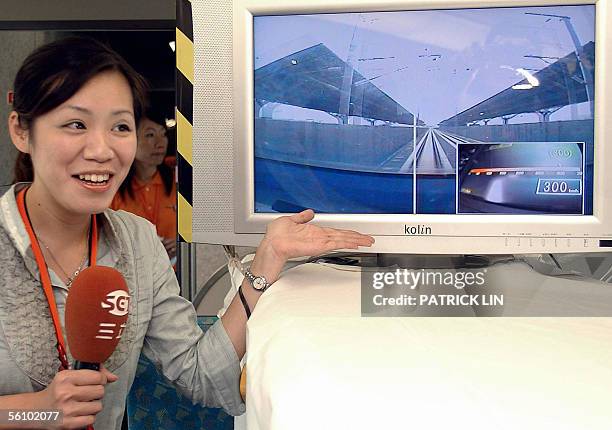 Taiwanese television reporter points to a TV screen displayed inside one of the island's "bullet trains" showing its speed of 300 kilometers per hour...