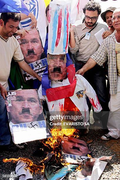 Activists burn a a dummy and portraits of US President George W.Bush depicted as Adolf Hitler in protest for his presence in the country 06 November,...