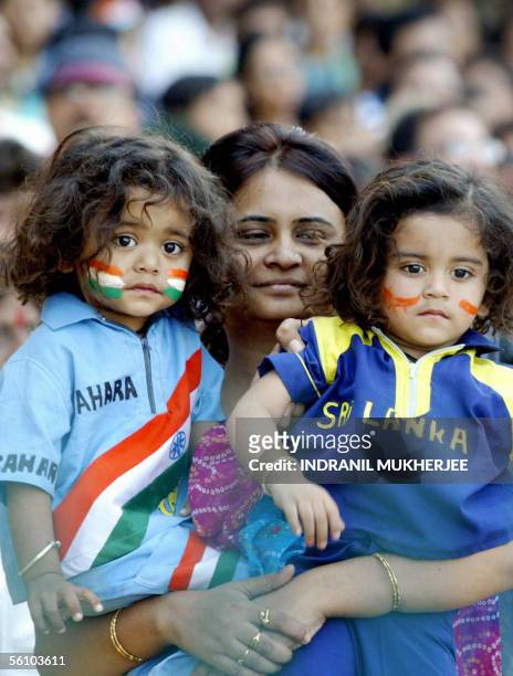 An Indian mother holds her twins dressed in Indian and Sri Lankan cricket uniforms during the fifth one day international match between India and Sri...