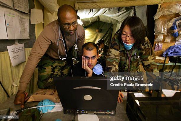 Dr. Eric McDonald , with 212 MASH, U.S Air Force with the 435th medical Group Dr. Fareed Sheikh and Dr. Mary Choi study the computer for medical...