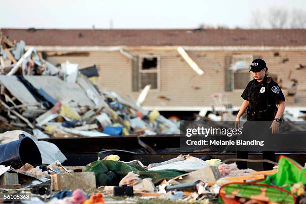 Police officer searches debris left by an early morning tornado that wiped out an estimated 140 homes at the East Brook Mobile Home Park November 6,...
