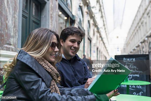 couple reading lunch menu in galeries royales saint-hubert, brussels, flanders, belgium - adult man brussels stock pictures, royalty-free photos & images