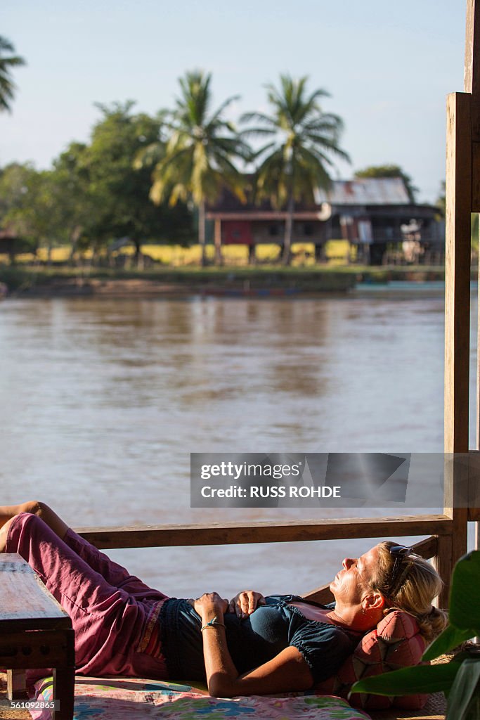 Female tourist sunbathing on Mekong houseboat, Don Det, Laos