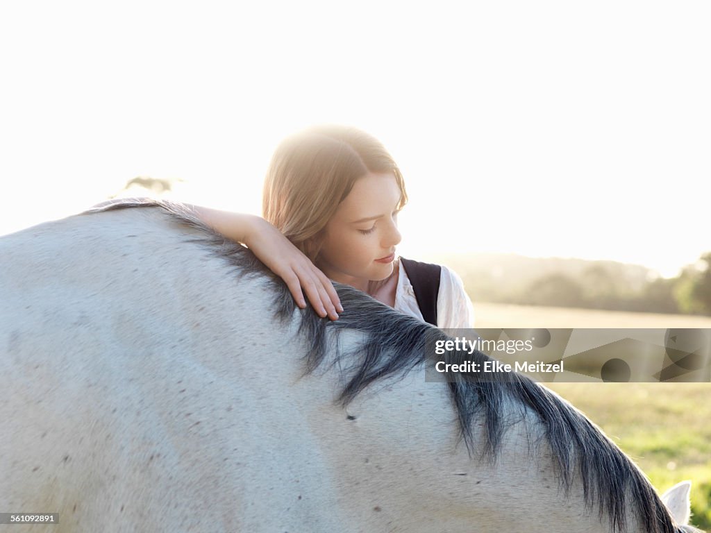 Portrait of teenage girl with grey horse