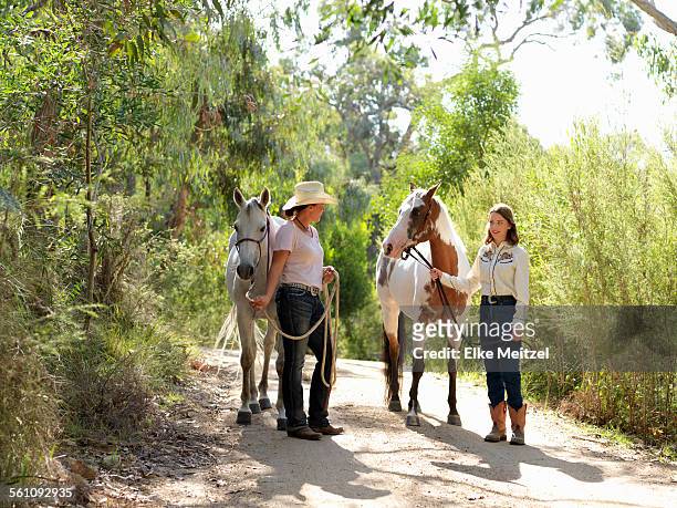 teenage girl and mother leading two horses on dirt track - australian light horse stock pictures, royalty-free photos & images