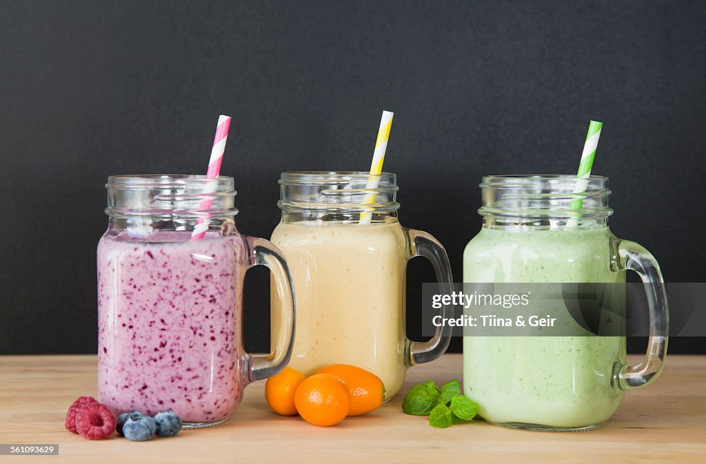 Still life of three fresh smoothies and fruit