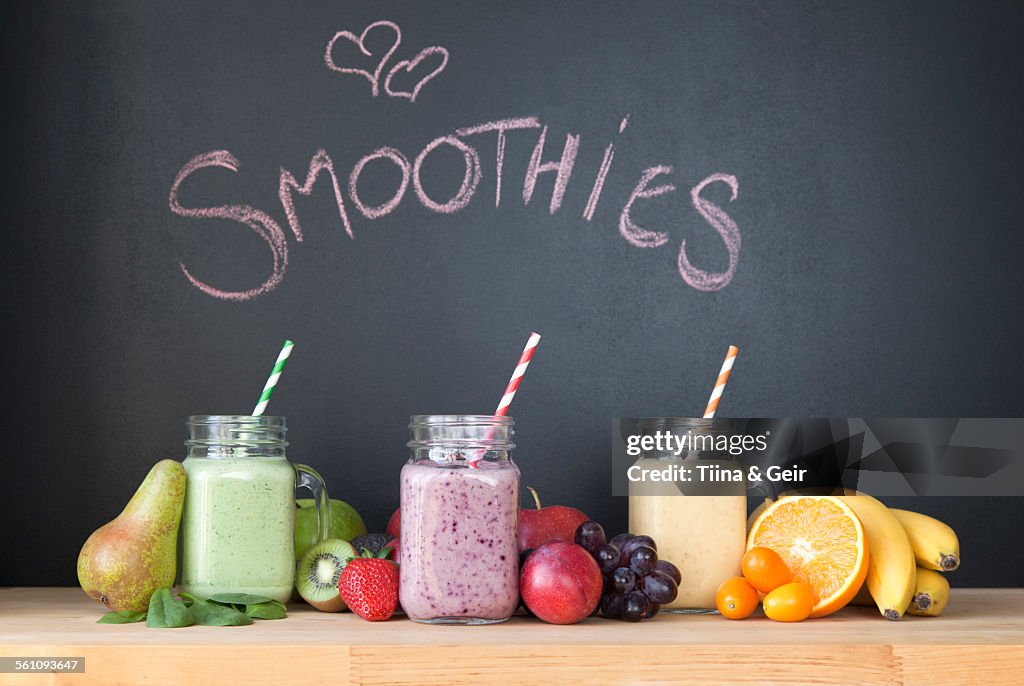 Still life of three fresh smoothies in front of blackboard