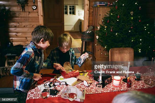 two brothers opening christmas presents at table - hemavan stock pictures, royalty-free photos & images