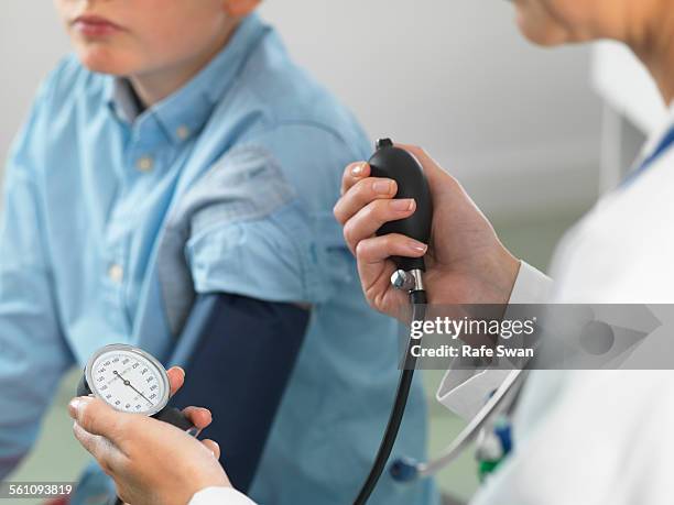 doctor reading blood pressure of young boy in clinic - womans clinic heart stockfoto's en -beelden