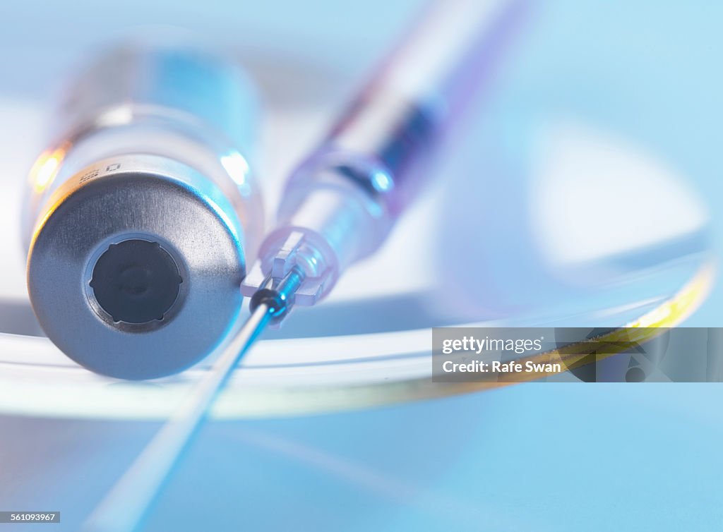 Vaccine and hypodermic syringe sitting on a glass dish