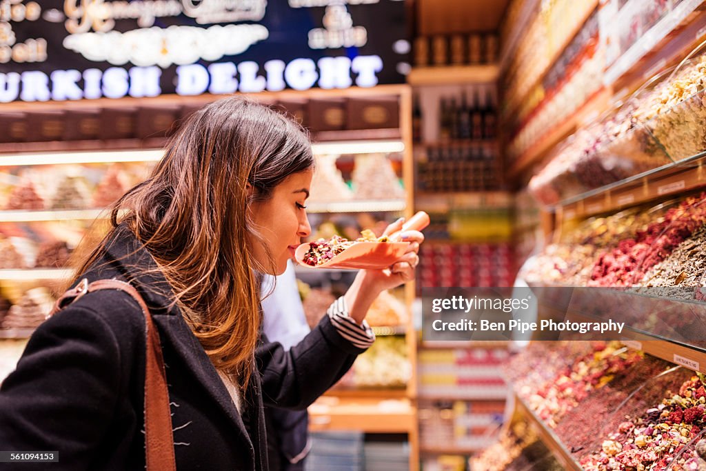 Young woman smelling food in market, Istanbul, Turkey