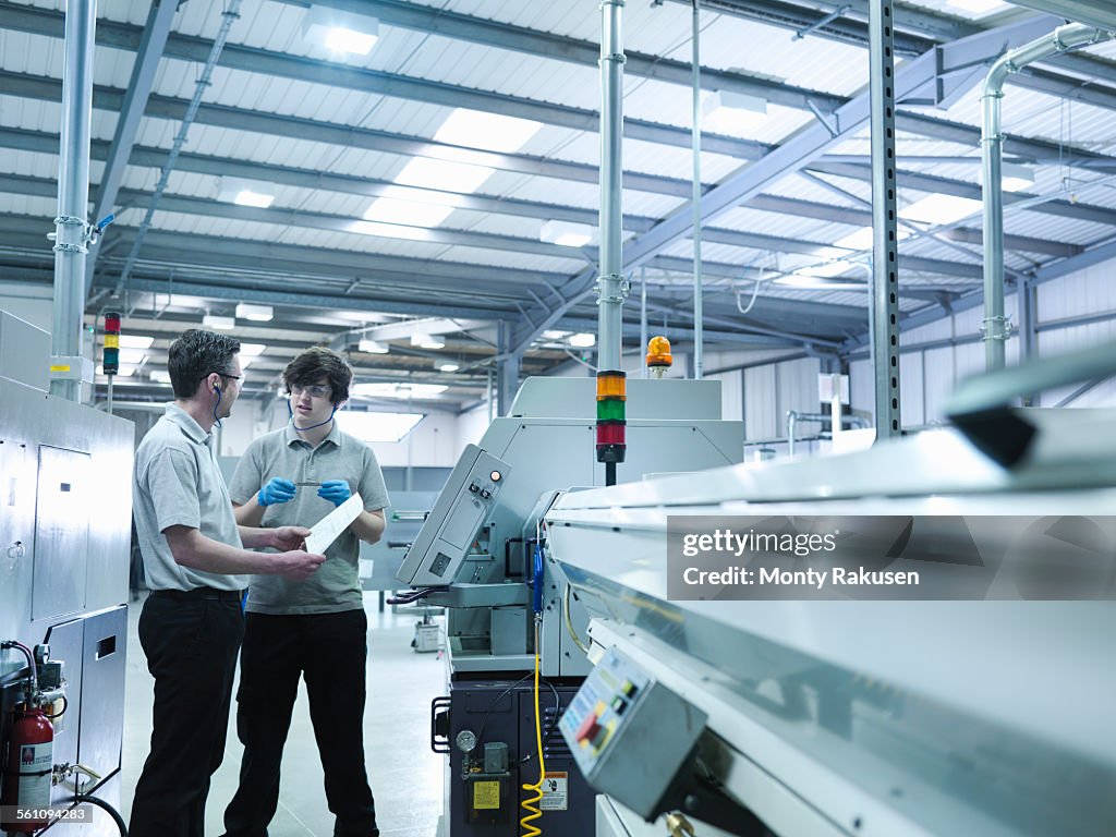 Engineer and apprentice in discussion in factory