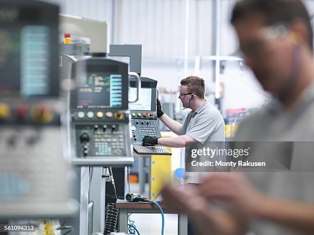 engineers operating cnc lathes in factory - drehmaschine stock-fotos und bilder