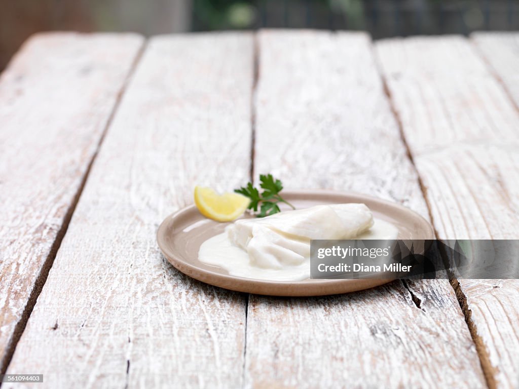 Plate of bake in bag haddock mornay on wooden table
