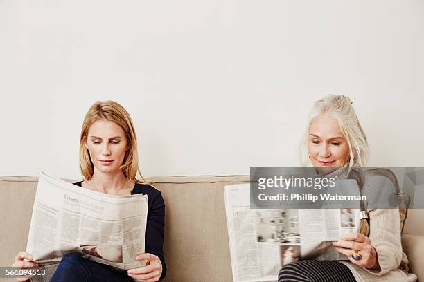 senior and mid adult women reading newspapers - woman hush stock pictures, royalty-free photos & images