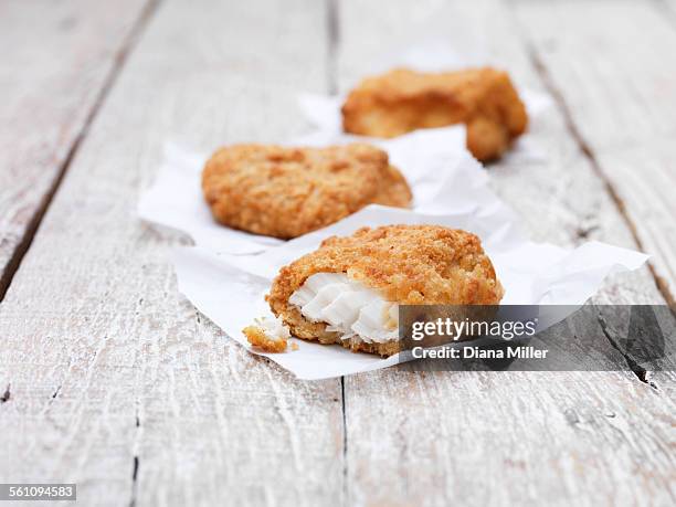 three fried breaded chunky cod pieces on wooden table - papel de cera imagens e fotografias de stock