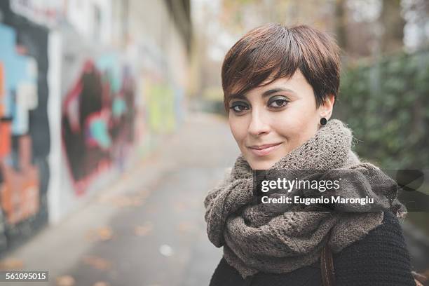 young woman on street, graffiti wall in background - girl power graffitti stock pictures, royalty-free photos & images