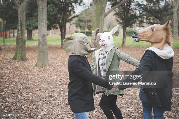 three sisters wearing animal masks dancing in park - animal friends stock-fotos und bilder