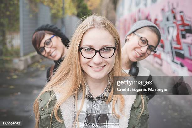 three sisters on street, graffiti wall in background - girl power graffitti stock pictures, royalty-free photos & images