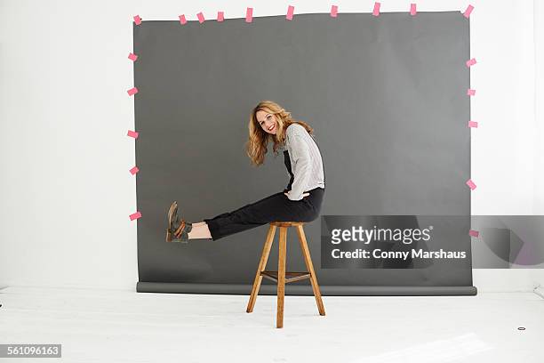 woman on stool in front of photographers backdrop - sitzen stock-fotos und bilder