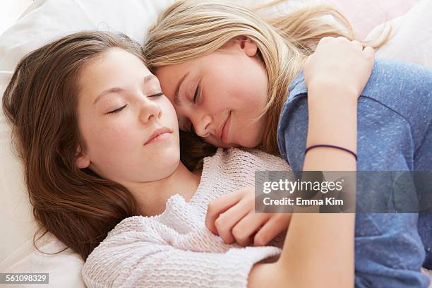 two girls lying on bed with eyes closed - nur kinder stock-fotos und bilder