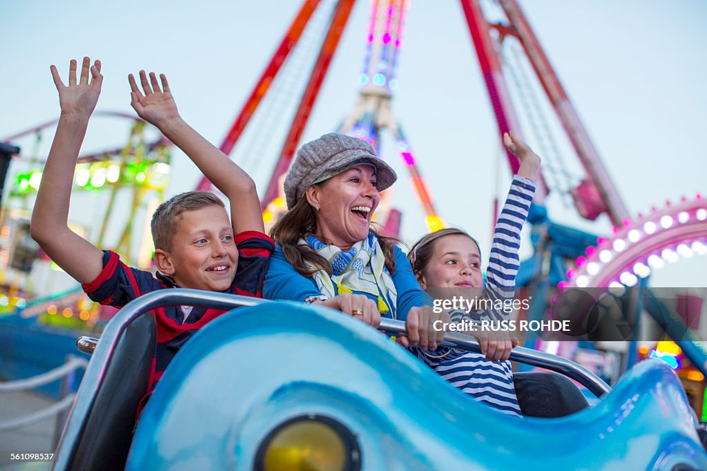 Mature woman with son and daughter on fairground ride