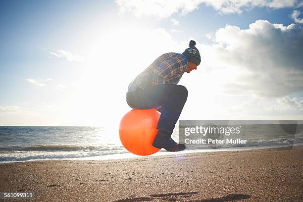 mature man jumping mid air on inflatable hopper at beach - hoppity horse 個照片及圖片檔