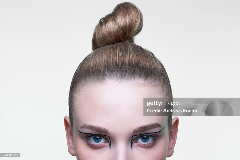 Young woman with her hair in a tight bun, cropped.