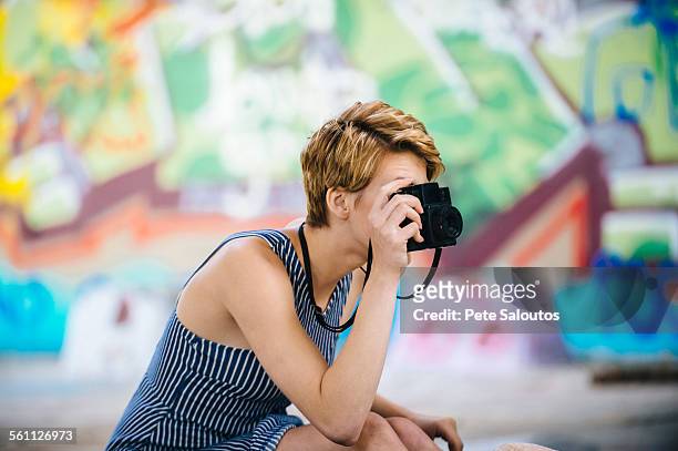 stylish teenage girl photographing with camera in front of graffiti wall - pete vandal stock-fotos und bilder