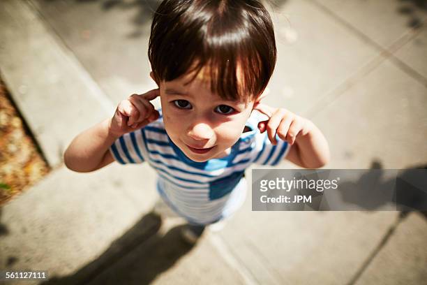 portrait of boy putting his fingers in his ears on street - fingers in ears 個照片及圖片檔