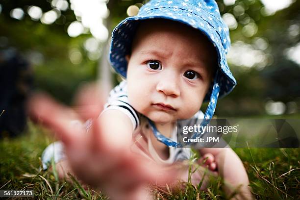 close up of baby boy reaching out towards camera - eenjarig plantenkenmerk stockfoto's en -beelden