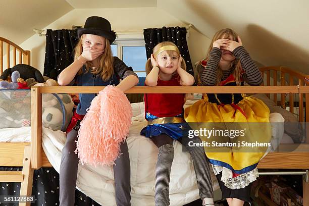 three sisters, sitting on bed, wearing fancy dress costumes, covering mouth, ears and eyes - hear no evil stock pictures, royalty-free photos & images