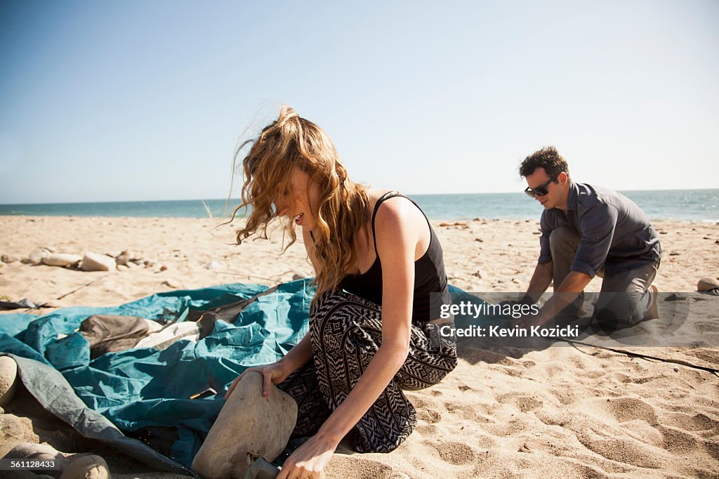 Couple setting up tent on beach, Malibu, California, USA