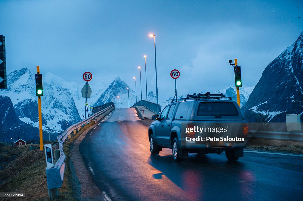 Vehicle crossing green light bridge at dusk, Reine, Lofoten, Norway